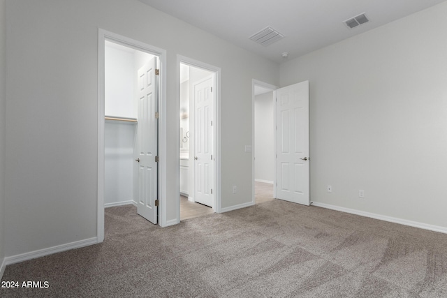 unfurnished bedroom featuring a walk in closet, carpet flooring, and a closet