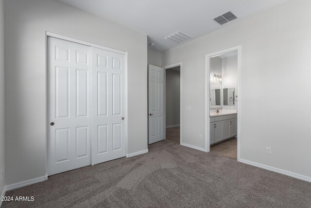 unfurnished bedroom with sink, light carpet, a closet, and ensuite bath