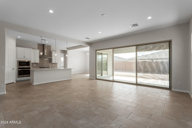 unfurnished living room featuring a wealth of natural light, sink, and light tile patterned flooring