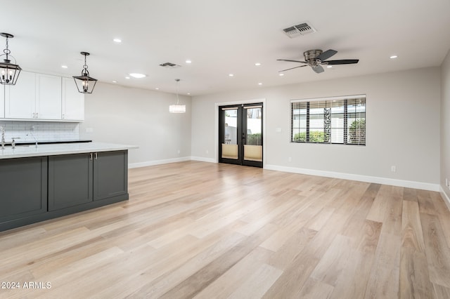 kitchen featuring pendant lighting, light hardwood / wood-style floors, white cabinets, backsplash, and ceiling fan