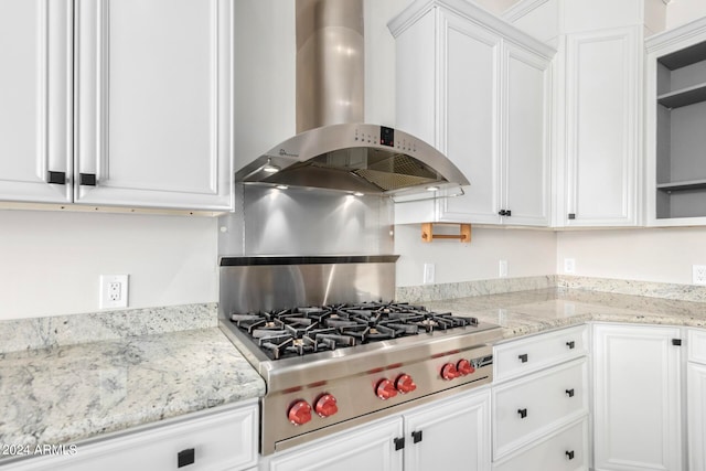 kitchen featuring wall chimney exhaust hood, light stone countertops, white cabinets, and stainless steel gas stovetop