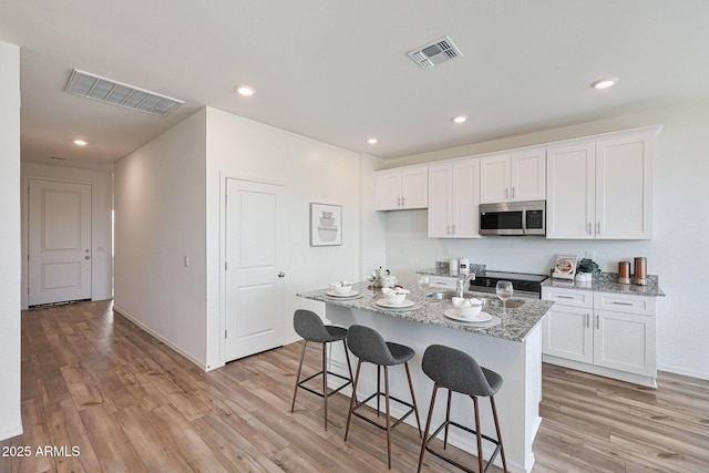 18052 W Sand Hills Rd, Surprise, AZ 85387 - kitchen featuring stainless steel microwave, light wood-style floors, and visible vents
