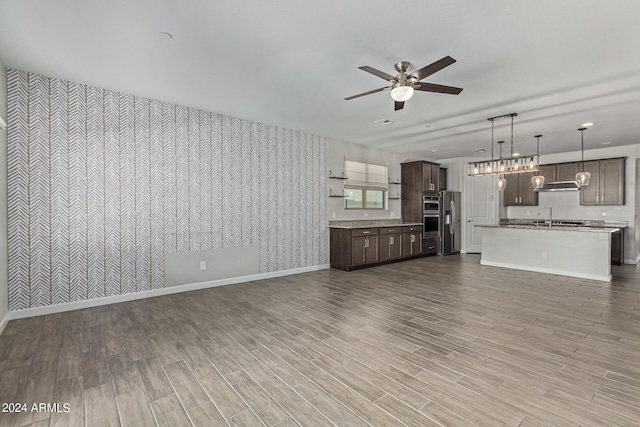 unfurnished living room featuring sink, ceiling fan, and light wood-type flooring