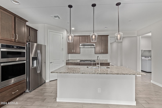 kitchen featuring hanging light fixtures, appliances with stainless steel finishes, sink, light stone counters, and washer / clothes dryer