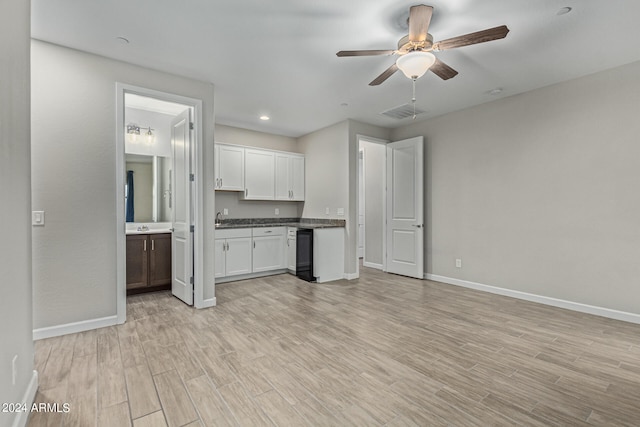 unfurnished living room featuring ceiling fan, sink, and light wood-type flooring