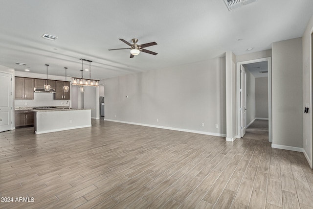 unfurnished living room with ceiling fan, sink, and light wood-type flooring