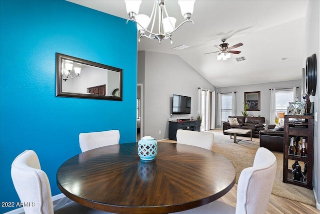 dining area with vaulted ceiling, ceiling fan with notable chandelier, and light wood-type flooring