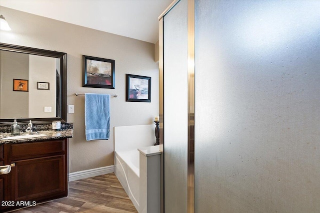 bathroom with a bath, wood-type flooring, and vanity