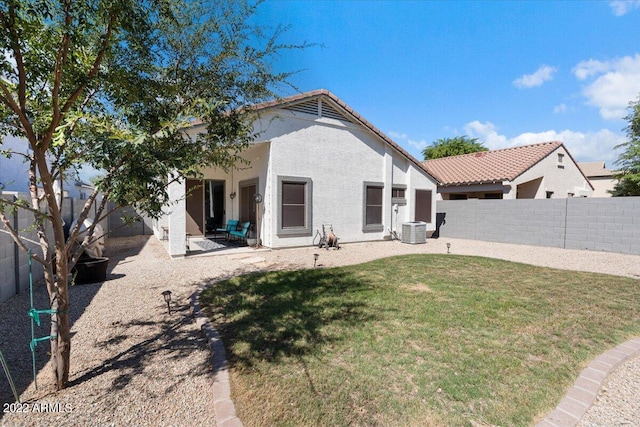 rear view of property featuring central air condition unit, a patio, and a lawn