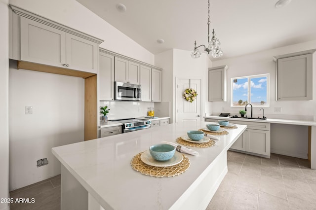38167 W San Juan Ave, Tonopah, AZ 85354 - kitchen with stainless steel appliances, gray cabinets, light countertops, decorative backsplash, and vaulted ceiling