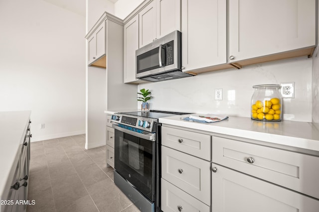 38167 W San Juan Ave, Tonopah, AZ 85354 - kitchen featuring stainless steel appliances, light countertops, light tile patterned floors, baseboards, and backsplash
