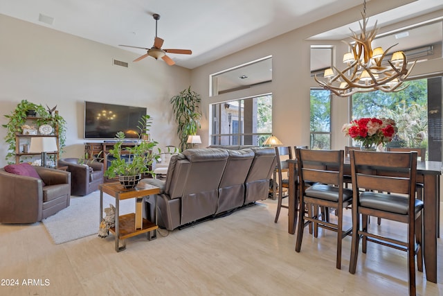 living room with ceiling fan with notable chandelier and light hardwood / wood-style flooring