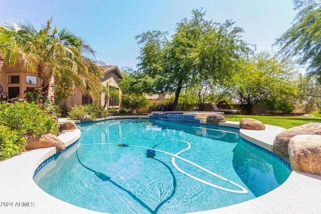 view of swimming pool featuring a lawn and an in ground hot tub