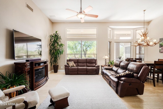 living room featuring a towering ceiling and ceiling fan with notable chandelier