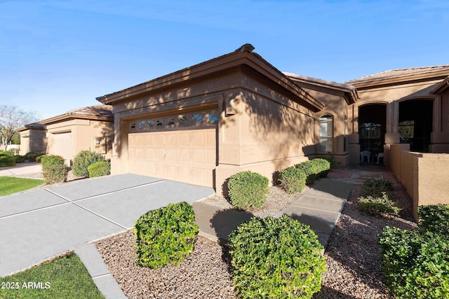 view of front of property with concrete driveway, an attached garage, and stucco siding