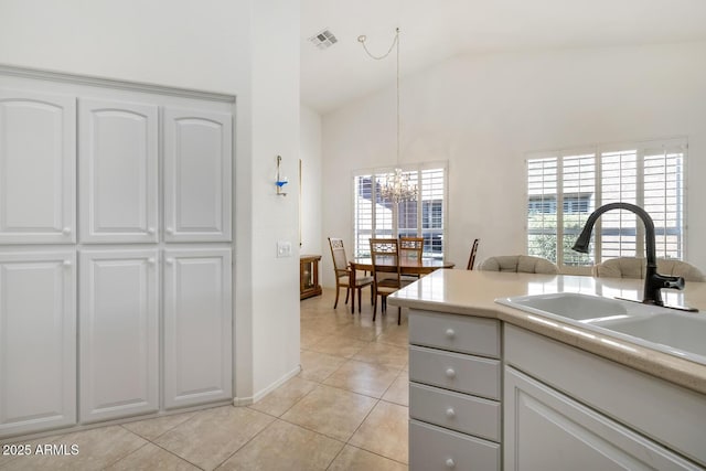 kitchen with light tile patterned floors, visible vents, a sink, vaulted ceiling, and a notable chandelier