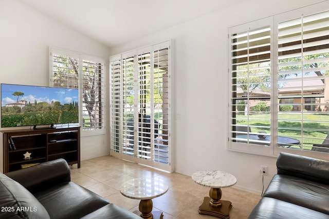living area with a healthy amount of sunlight, vaulted ceiling, and tile patterned flooring