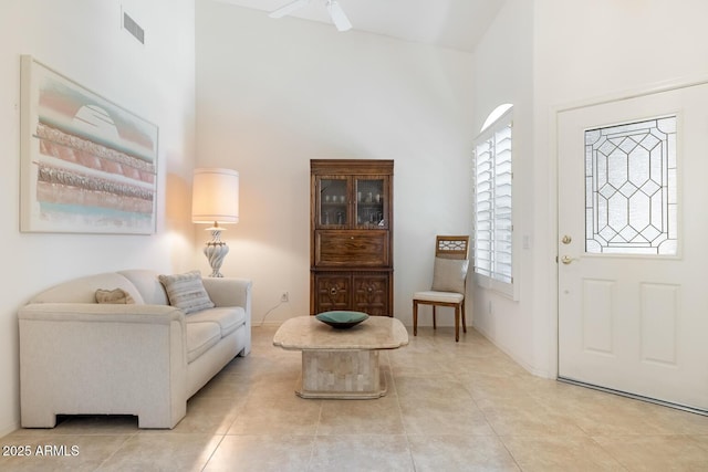 entrance foyer featuring light tile patterned flooring, visible vents, and a towering ceiling