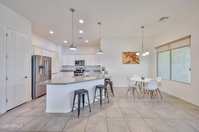 17082 S 182nd Ave, Goodyear, AZ 85338 - kitchen with stainless steel appliances, white cabinets, recessed lighting, light tile patterned flooring, and a breakfast bar area