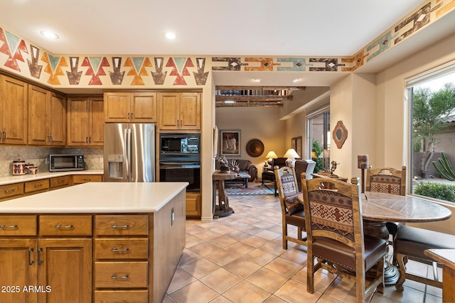 kitchen with a kitchen island, light tile patterned floors, backsplash, and black appliances