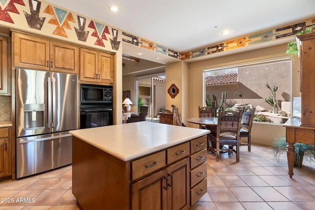 kitchen featuring backsplash, light tile patterned floors, a kitchen island, and black appliances