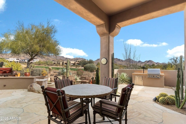 view of patio with exterior kitchen, a mountain view, and area for grilling