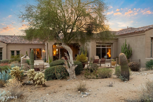 back house at dusk featuring a patio