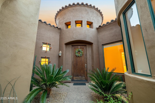 entrance to property featuring stucco siding and a tiled roof