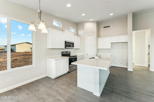 kitchen with a center island with sink, visible vents, appliances with stainless steel finishes, white cabinetry, and a sink