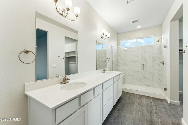 full bath with a marble finish shower, visible vents, a sink, and wood finished floors