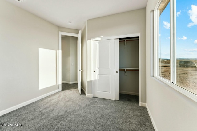 unfurnished bedroom with a closet, carpet flooring, multiple windows, and baseboards