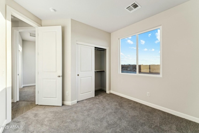 unfurnished bedroom with carpet floors, baseboards, visible vents, and a closet