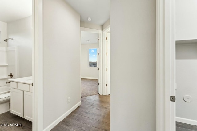 hallway featuring dark wood finished floors and baseboards