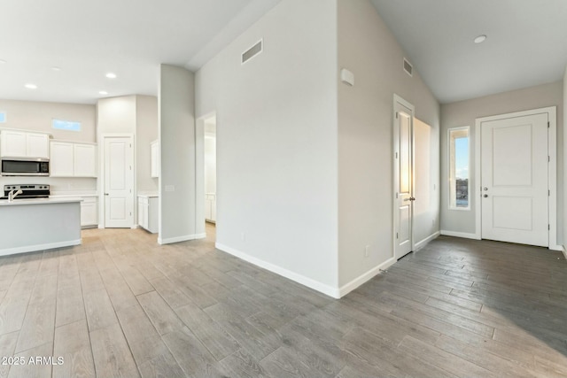 foyer entrance featuring baseboards, visible vents, and light wood finished floors