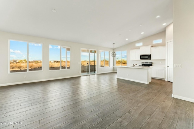 kitchen featuring an island with sink, stainless steel appliances, dark wood-type flooring, and open floor plan