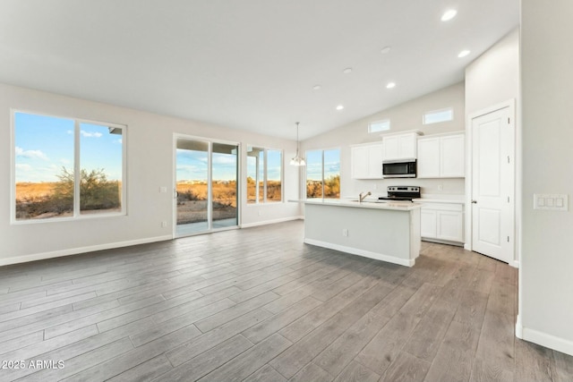 kitchen featuring white cabinets, light wood-style flooring, open floor plan, a kitchen island with sink, and stainless steel appliances