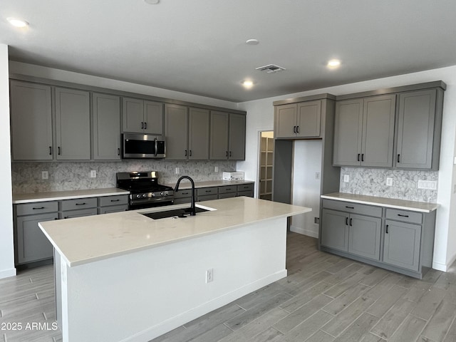 17481 W Fulton St, Goodyear, AZ 85338 - kitchen with appliances with stainless steel finishes, gray cabinetry, light wood-style flooring, a sink, and tasteful backsplash