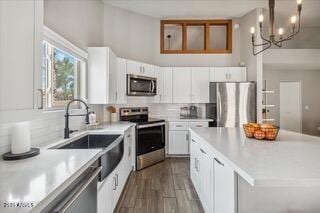 kitchen with pendant lighting, stainless steel appliances, a center island, and white cabinets