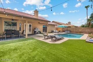 rear view of house featuring a patio, a fenced in pool, and a lawn