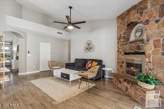 living room featuring lofted ceiling, hardwood / wood-style flooring, a fireplace, and ceiling fan