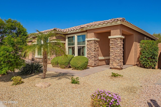 mediterranean / spanish home with a tile roof, stone siding, and stucco siding