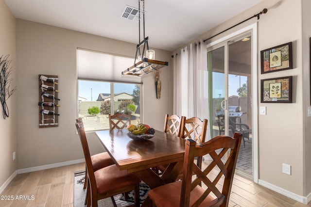 dining space with visible vents, light wood-style flooring, and baseboards