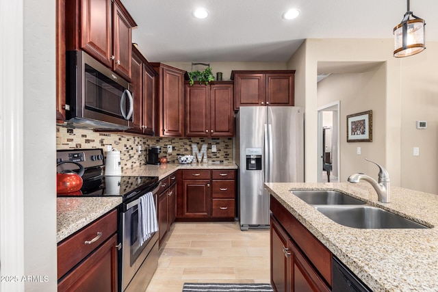 kitchen with light stone countertops, pendant lighting, decorative backsplash, appliances with stainless steel finishes, and a sink