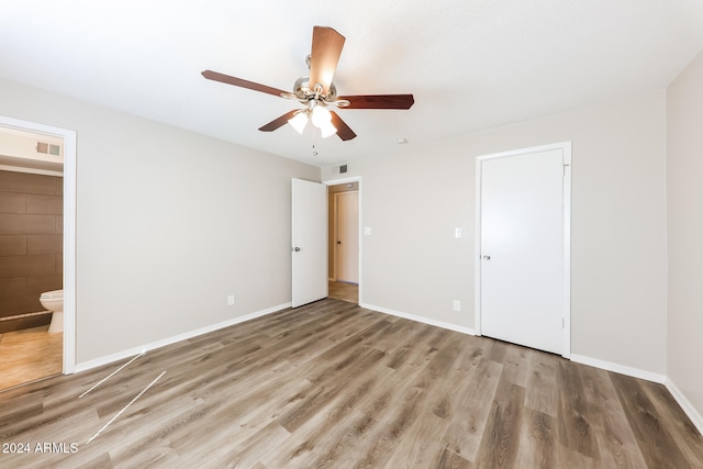 unfurnished bedroom with ceiling fan, hardwood / wood-style flooring, a closet, and ensuite bath