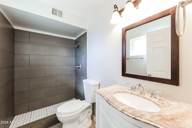 bathroom featuring vanity, toilet, and tiled shower