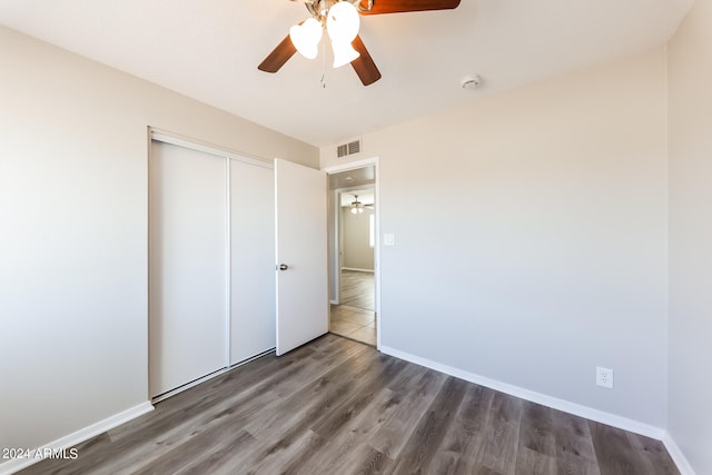 unfurnished bedroom with ceiling fan, a closet, and dark hardwood / wood-style flooring