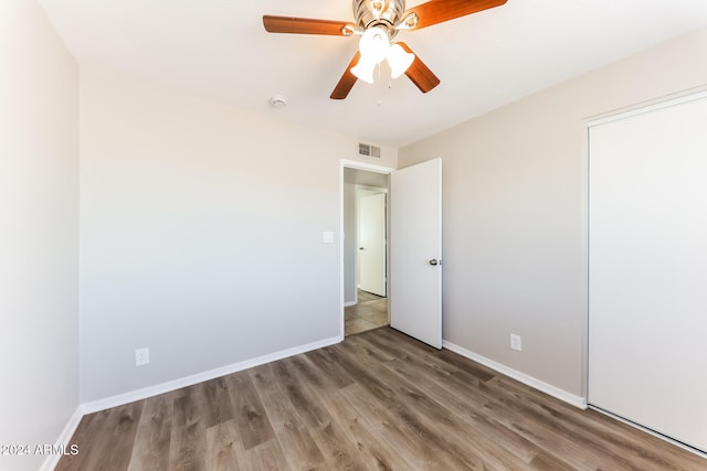 unfurnished bedroom featuring wood-type flooring, a closet, and ceiling fan