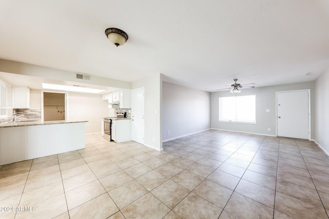 unfurnished living room with sink, light tile patterned floors, and ceiling fan