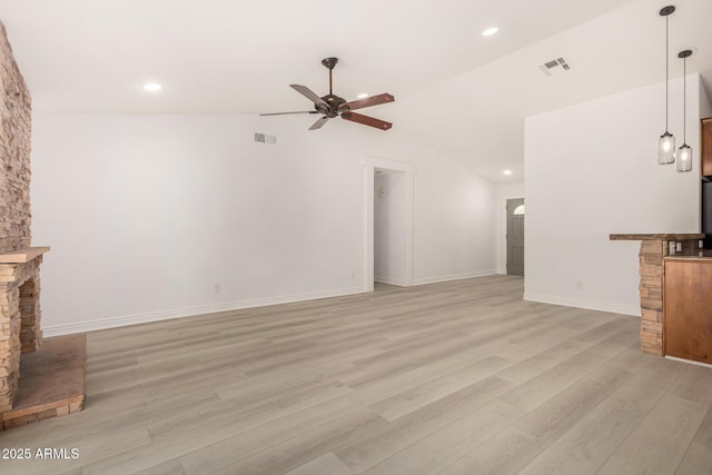 unfurnished living room featuring ceiling fan, light hardwood / wood-style floors, a stone fireplace, and lofted ceiling