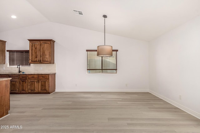 unfurnished dining area featuring light hardwood / wood-style floors, lofted ceiling, and sink